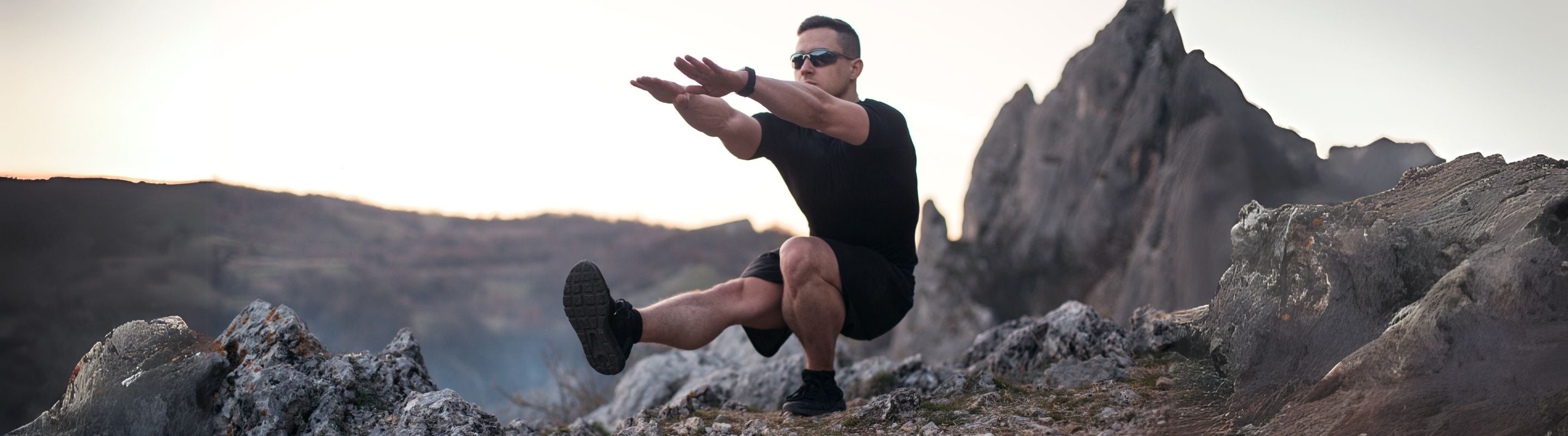 man doing single-leg squats on a mountain