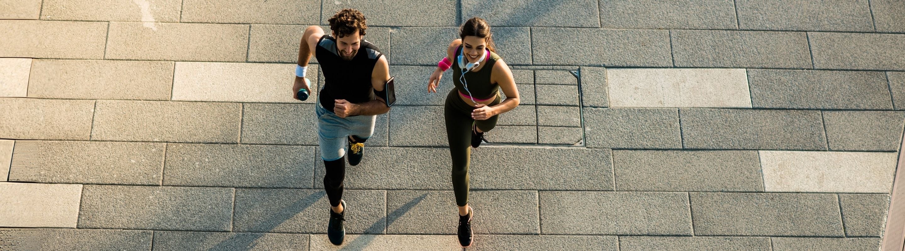 Aerial image of a man and woman running on the street. The ground under them is stone tile
