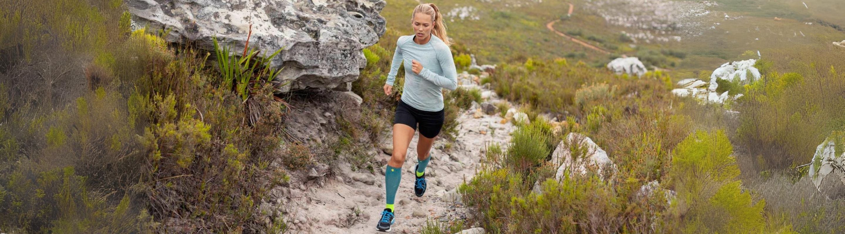 Ma and woman training for a marathon, running along a road near an overpass. They are wearing Bauerfeind compression sleeves