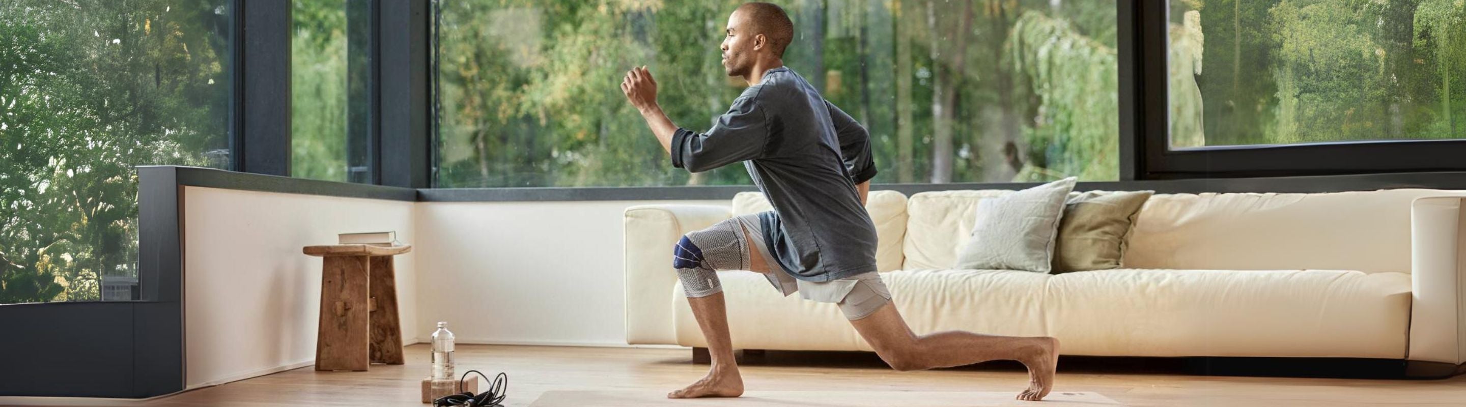 Man doing lunges in the living room. He is wearing a compression knee brace