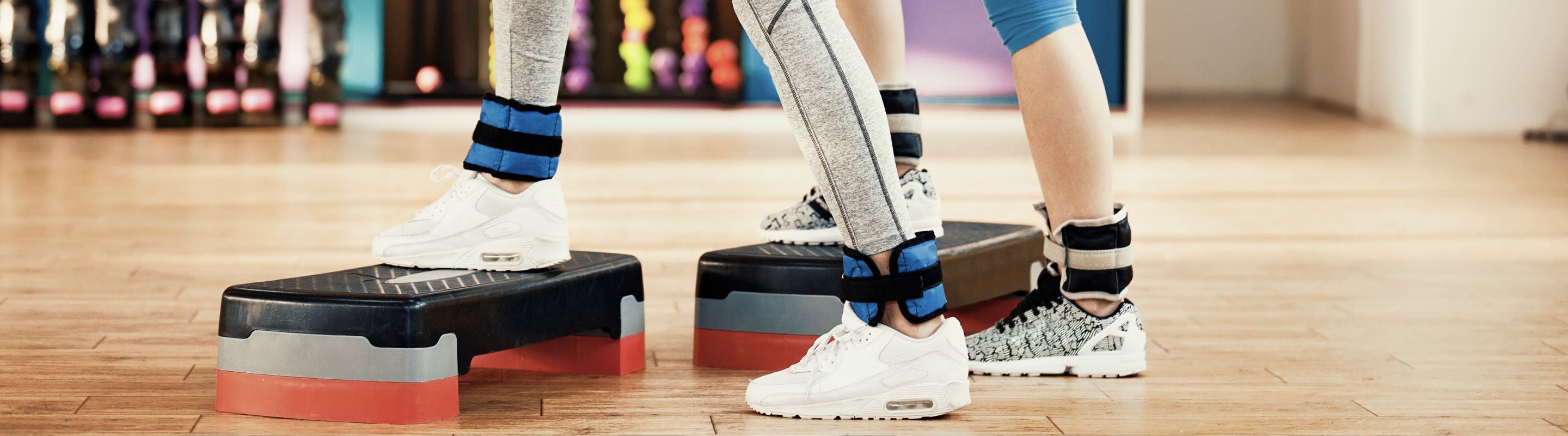 Two people at the gym stepping onto exercise steps