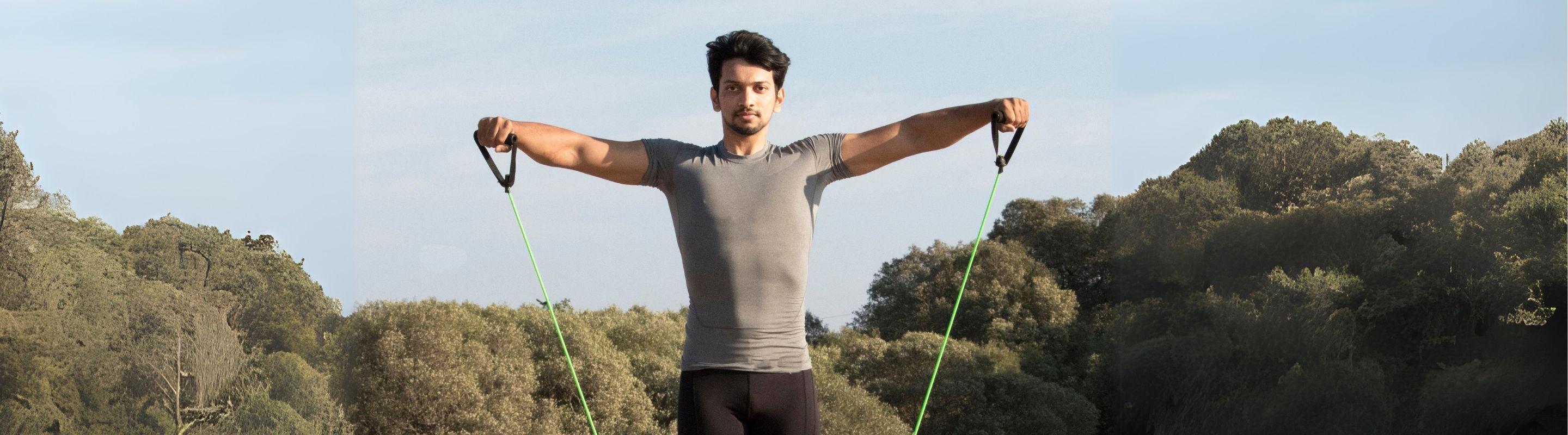 Man doing shoulder abductions workout at the park on a sunny day
