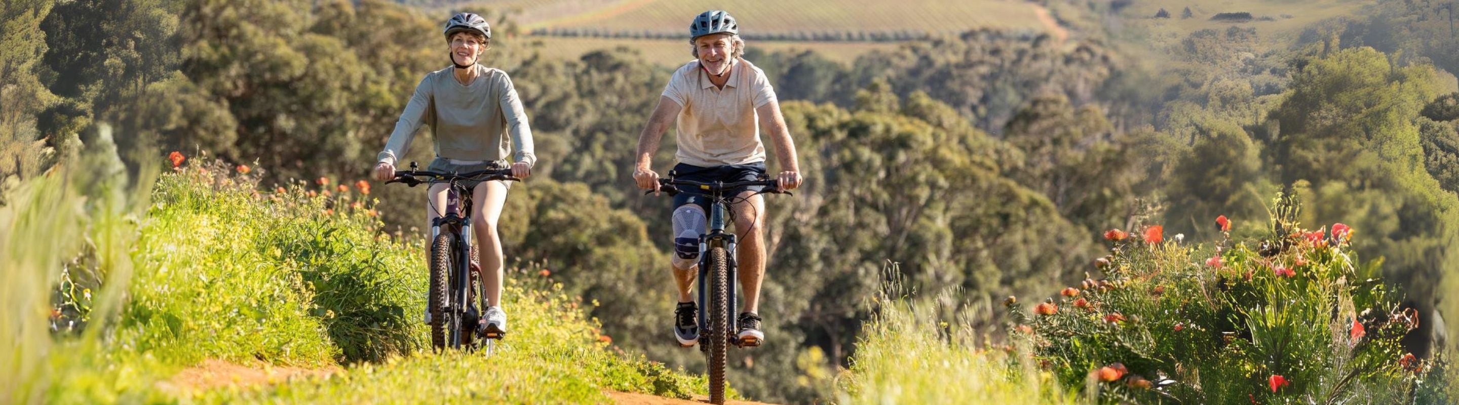 Two people cycling through grassy hills. One is wearing Bauerfeind's GenuTrain Knee Brace