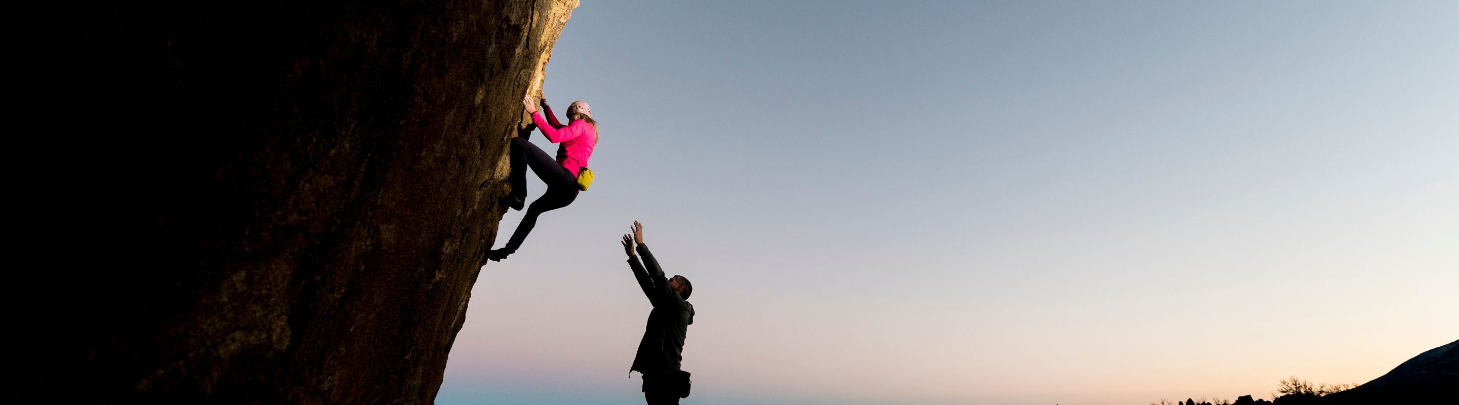 Woman in a red shirt Bouldering up a tall boulder