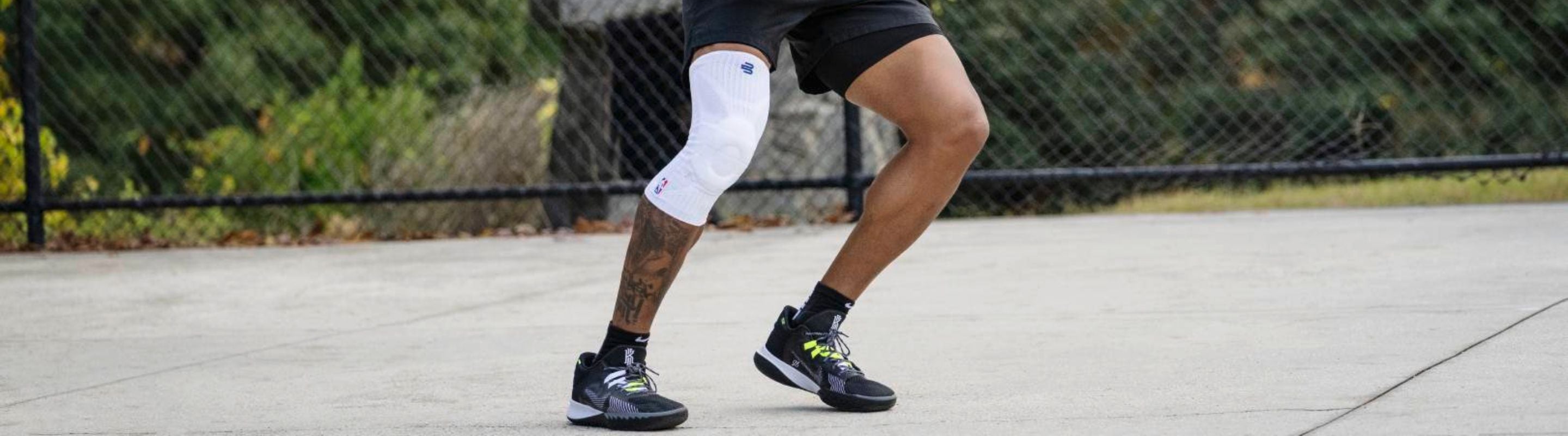 Man playing basketball. He's holding the bakk and looks like he's about to run. He' wearing Bauerfeind's sports knee compression sleeves
