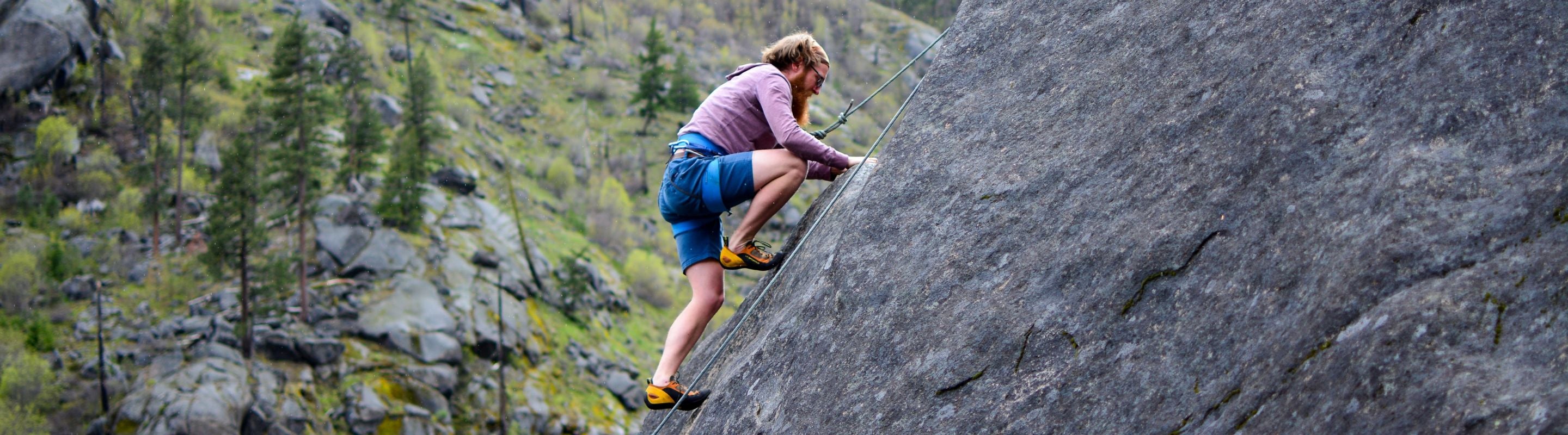 Man climbing up a steep rocky mountain.