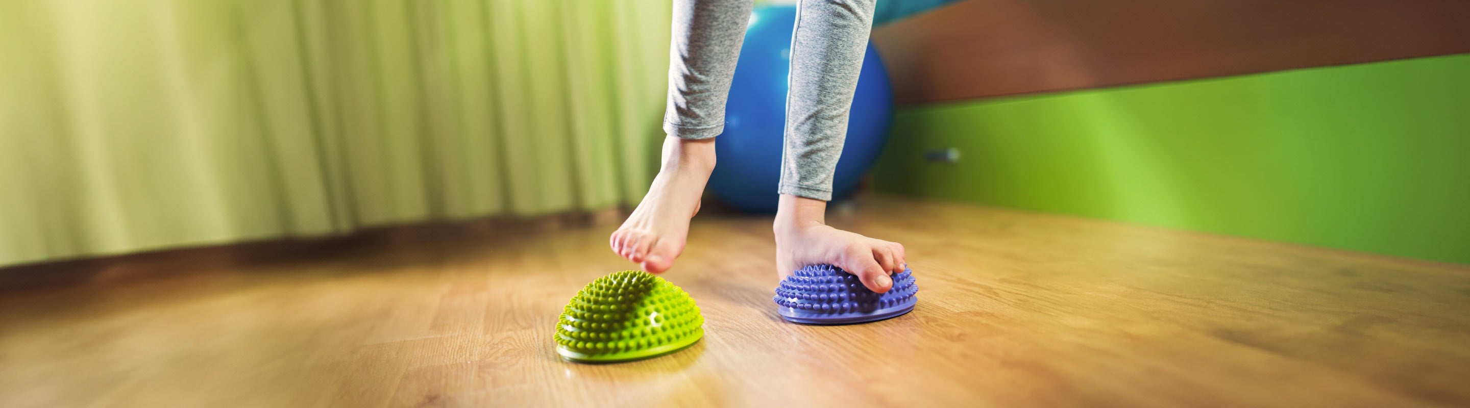 Person doing flat feet exercises on spiky massage balls to improve the condition.