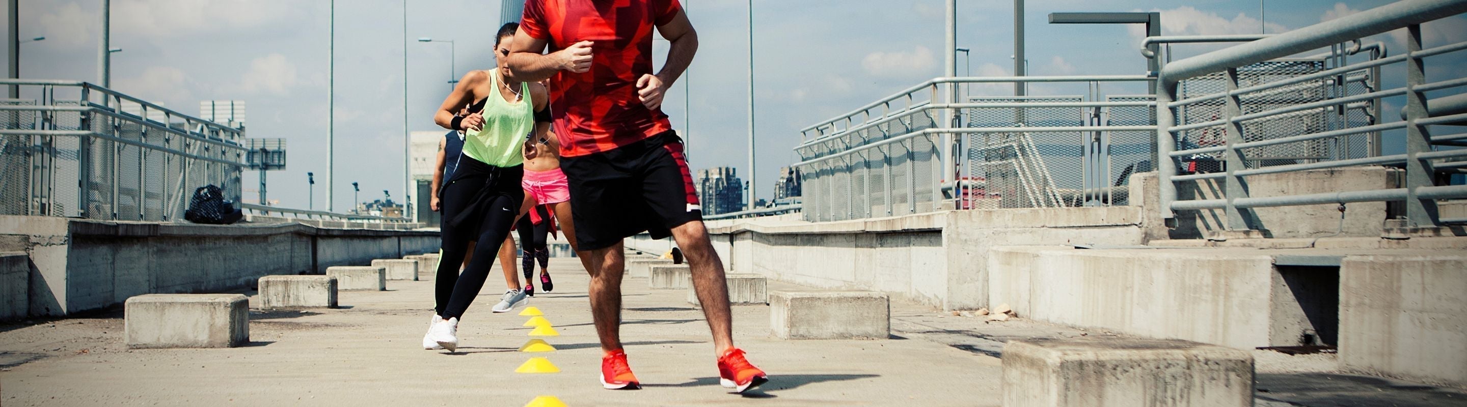 people doing agility training at a concrete park. They are running side to side between some cones