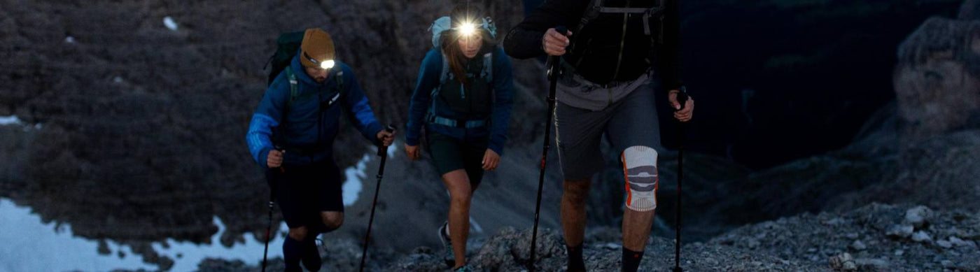 people hiking in the dark, in some snowy mountains. They are wearing Bauerfeind sports compression supports.