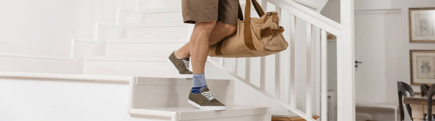 man walking down the stairs. He is wearing Bauerfeind's MalleoTrain Ankle Brace to reduce ankle swelling