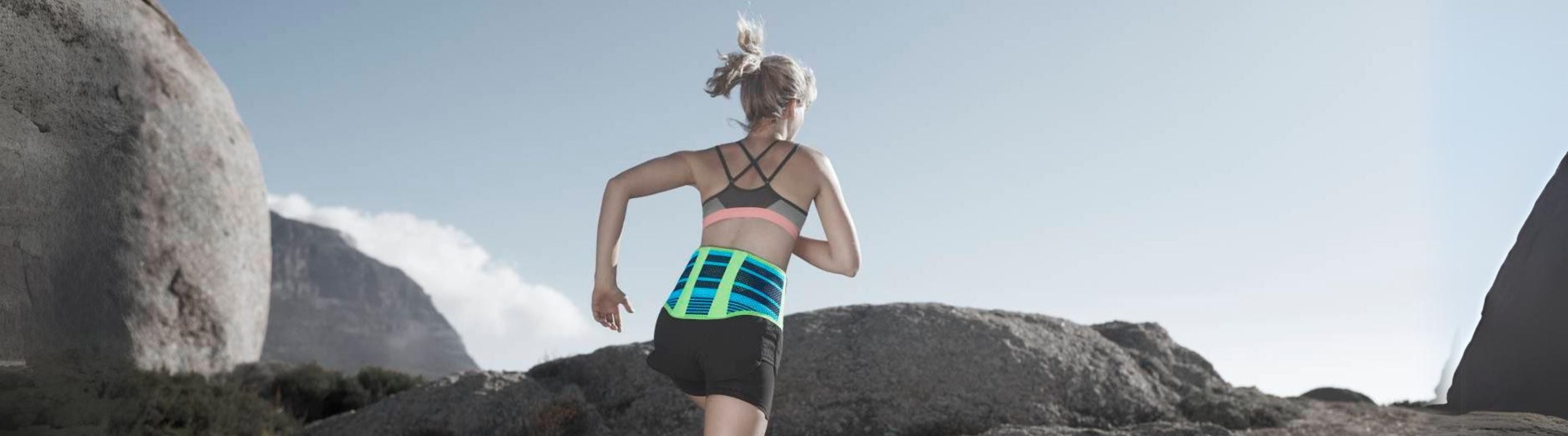 woman running up a rocky slope while wearing Bauerfeind's Sports Back Support