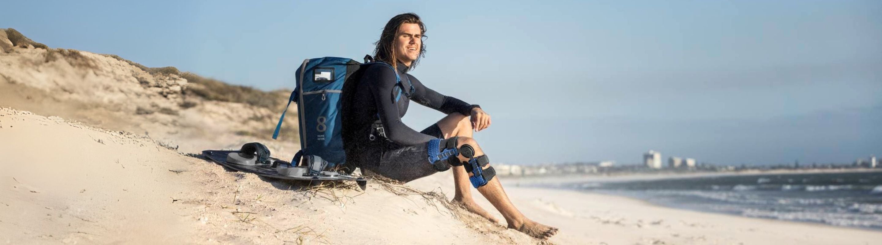 Man sitting on a beach wearing the SecuTec Genu Knee Brace for ACL damage