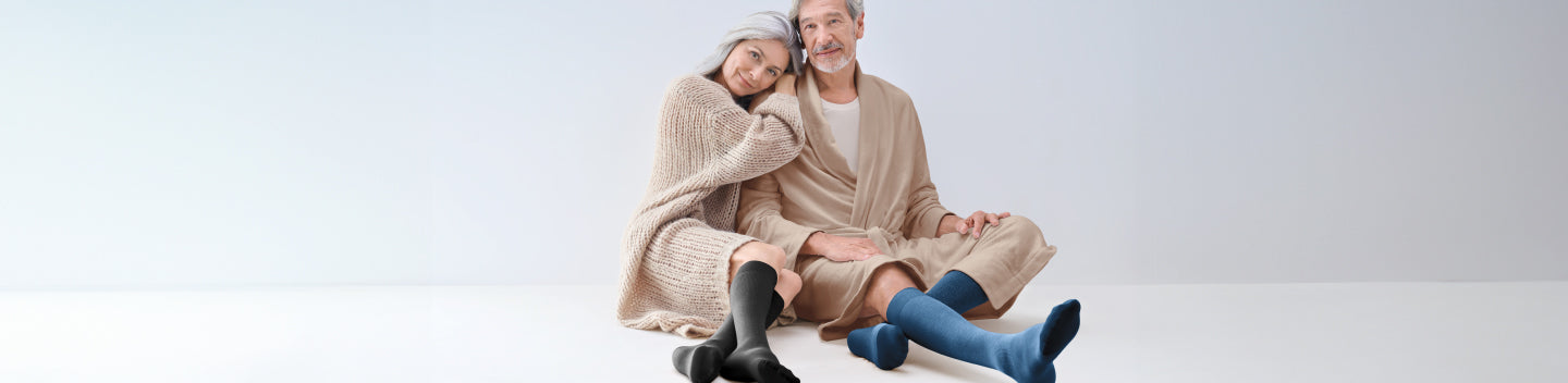 Man and woman wearing compression socks while snuggled under a blanket. Why do Varicose Veins Ache Most at Night?