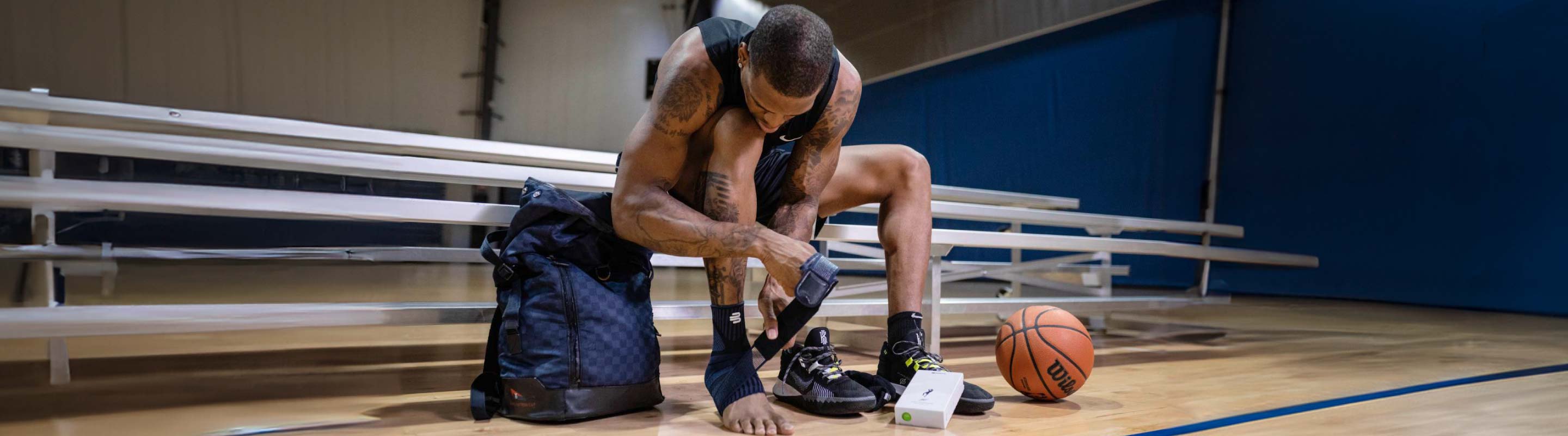 person sitting on a step and putting on Bauerfeind's Sports Ankle Support