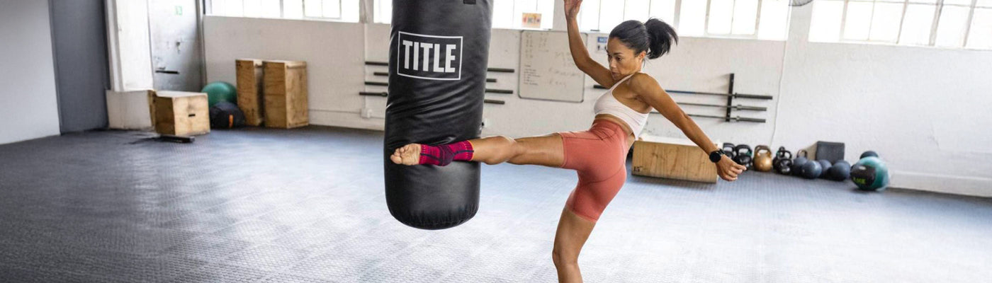 woman training for martial arts. She is kicking a punching bag while wearing a compression ankle brace