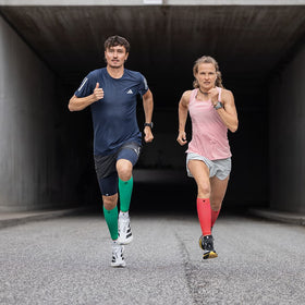 a guy and girl running while wearing Bauerfeind compression calf sleeves
