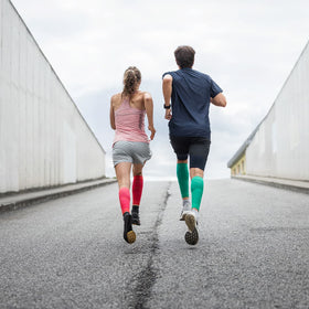 a girl and a guy running wearing Bauerfeind compression calf sleeves