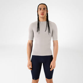 Person wearing a grey Bauerfeind compression short-sleeve top and navy shorts on a white background.