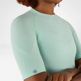 Light green Bauerfeind compression shirt worn by a person on a white background
